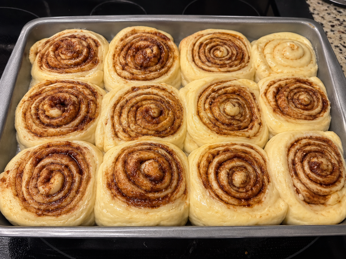 Twelve cinnamon rolls in a 9 by 13 pan after second rise